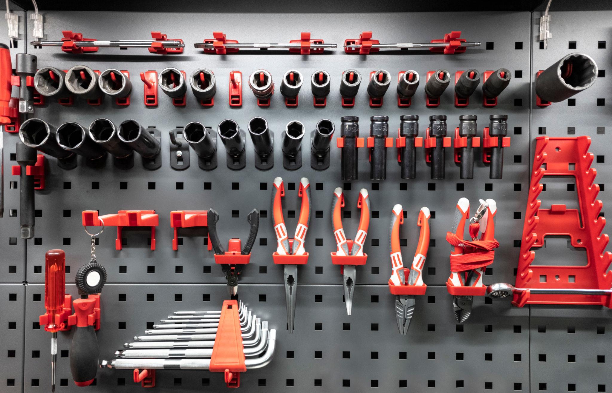 Mechanic hand tools set foundation — combination wrenches, screwdrivers, pliers, and ball-peen hammer on a steel workbench