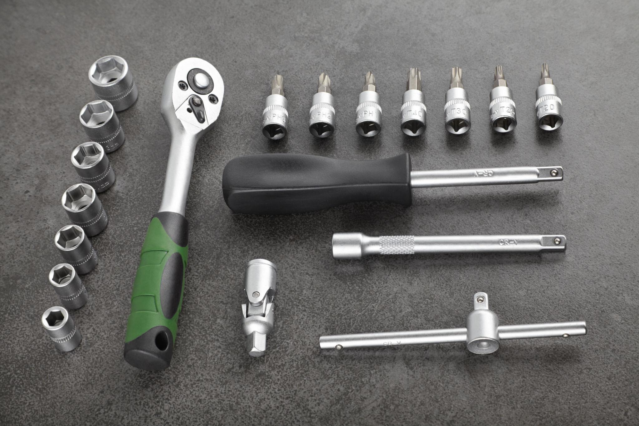 Professional ratchet set with extensions and universal joints — 1/4, 3/8, and 1/2 inch drive sizes on a foam tool tray in a workshop