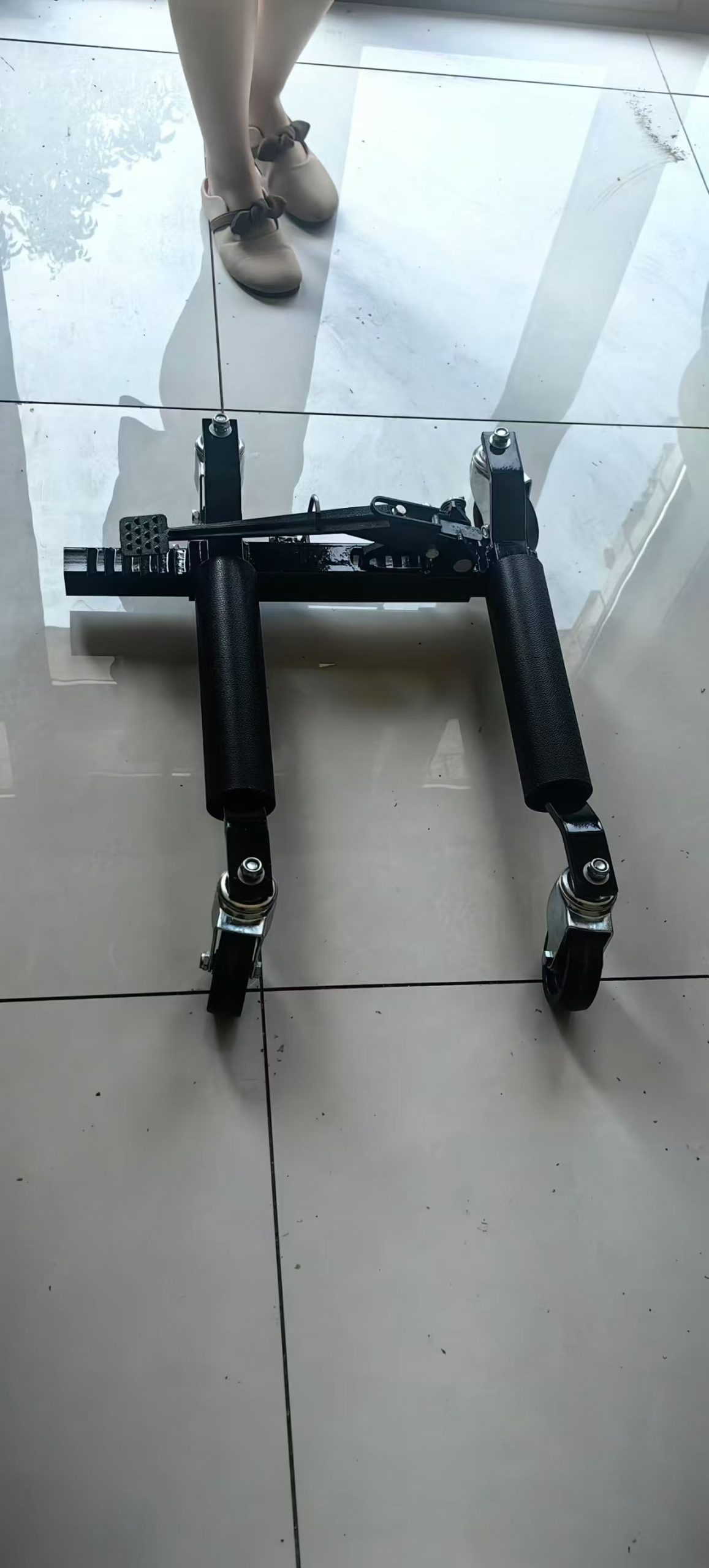Black positioning dolly with four caster assemblies viewed from above