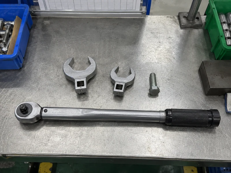 Two crowfoot offsets beside a detached torque wrench and fastener