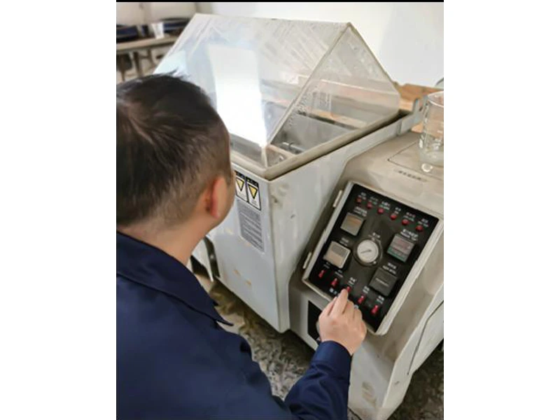 Operator beside an open salt-spray test chamber
