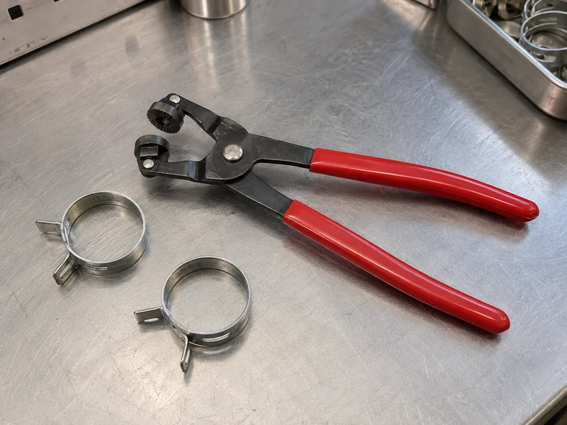 Spring hose clamp pliers beside loose flat-band spring clamps